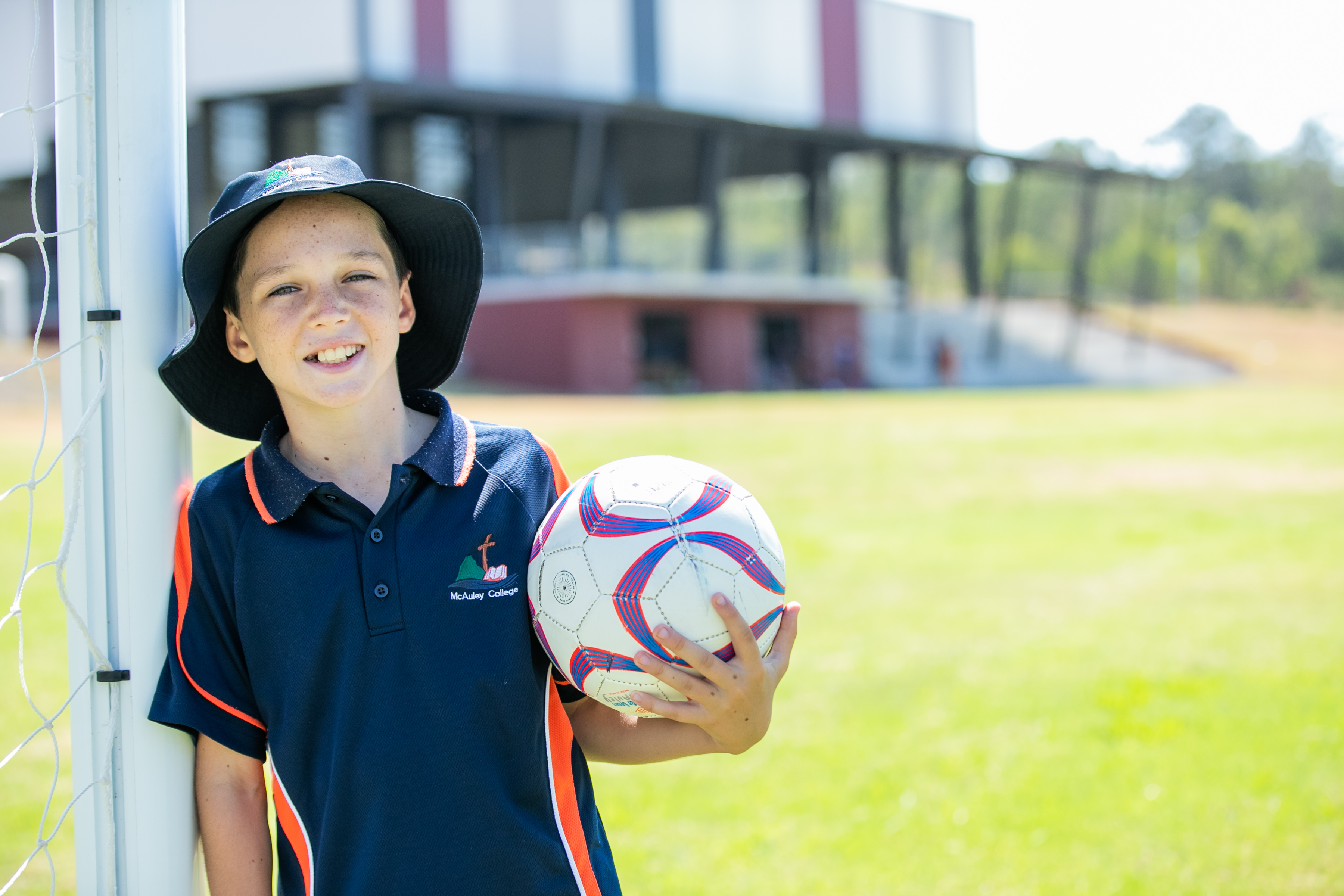 Student leaning against a post and holding a football.